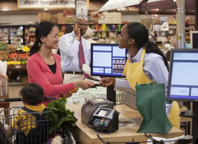 Mother and son paying cashier at supermarket